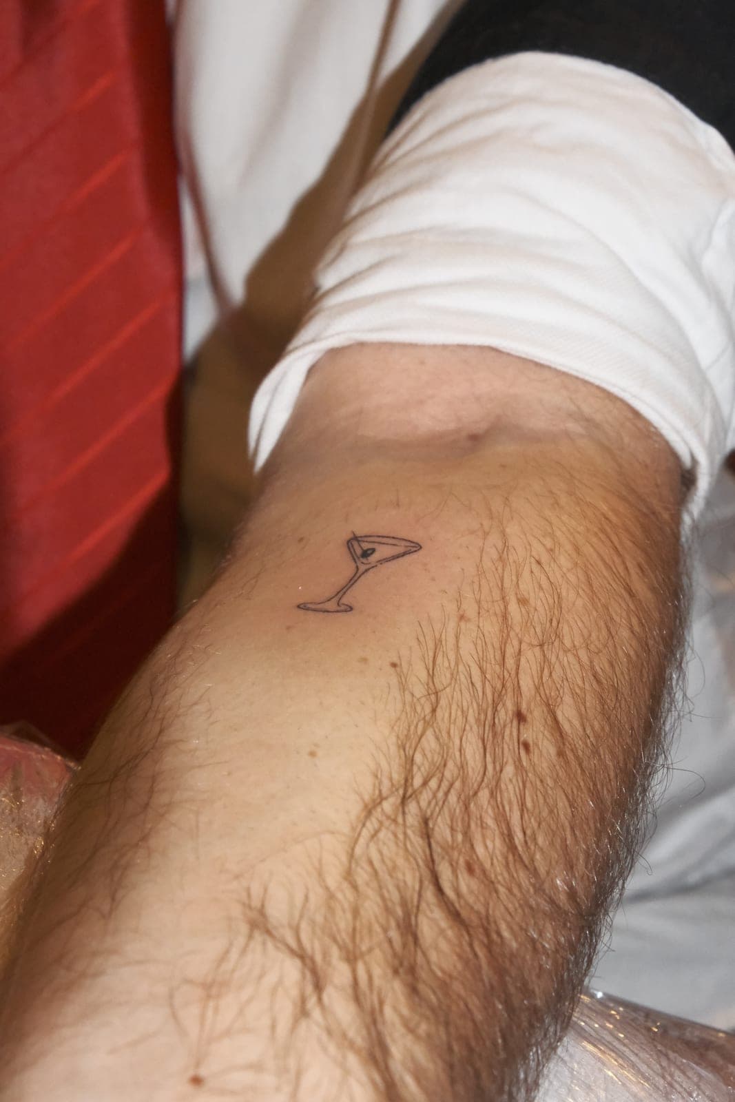 Pequena tatuagem de um copo no antebraço de um convidado