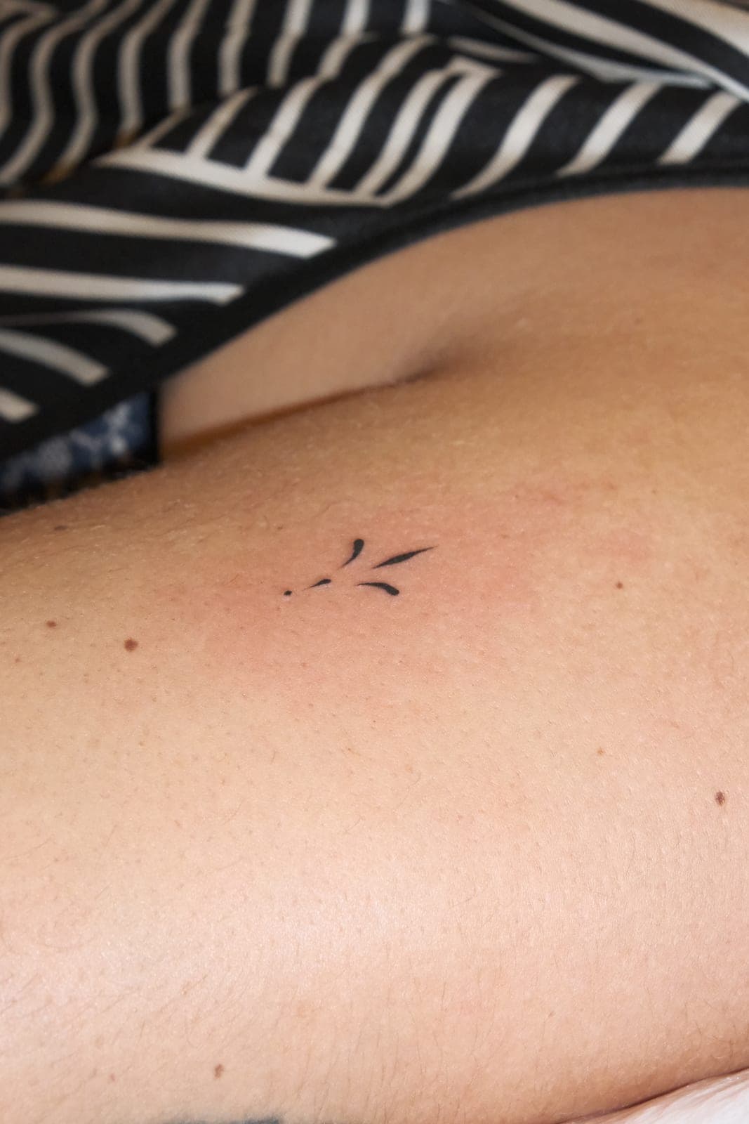 Pequena tatuagem de traços no braço de uma convidada