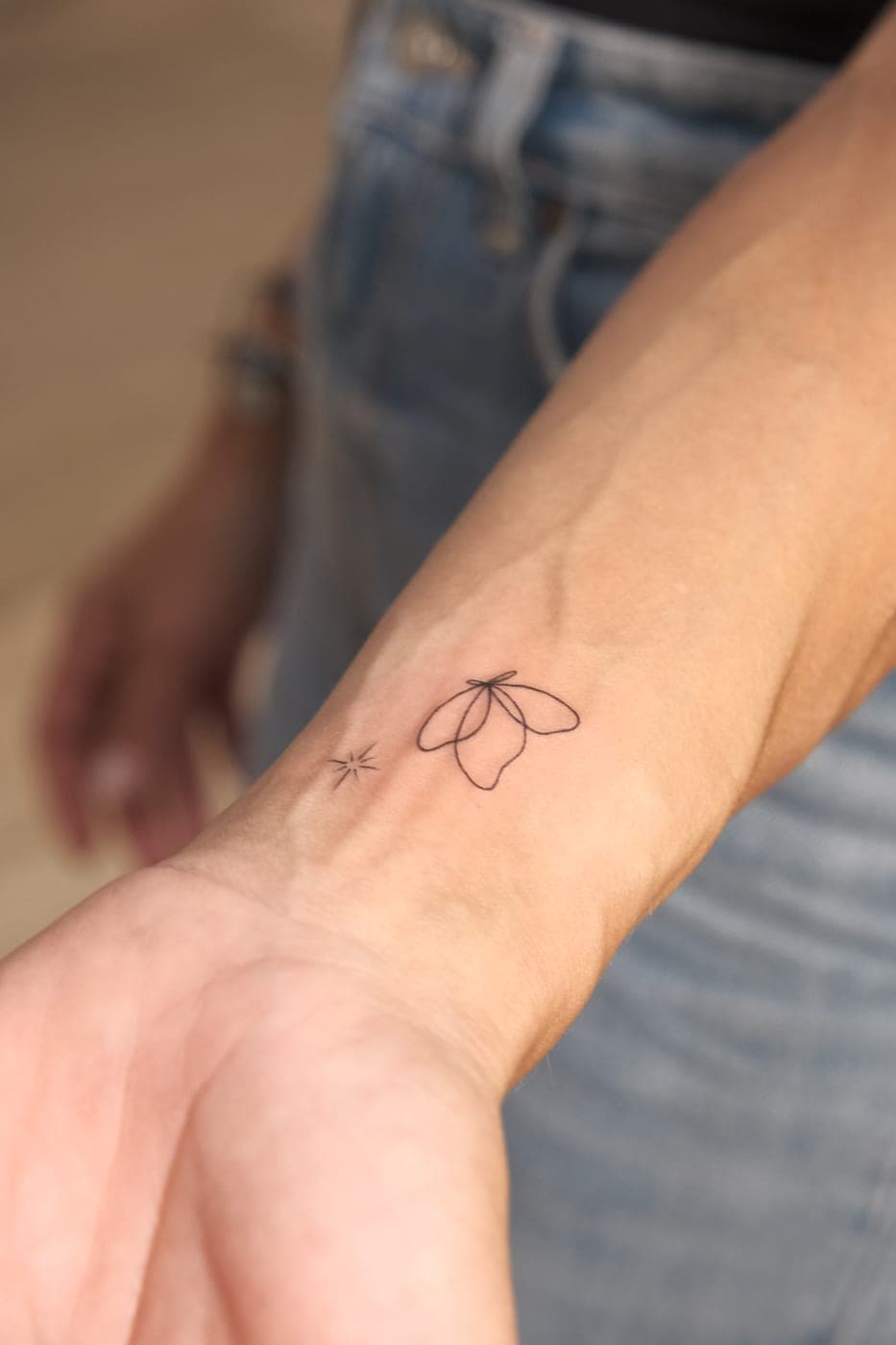 Pequena flor em fine line no pulso