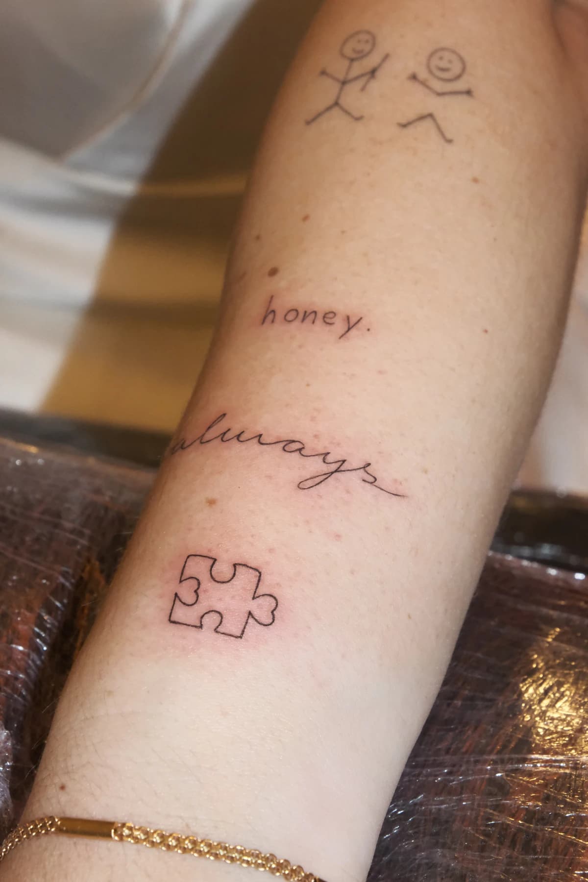 Conjunto de pequenas tatuagens em traço fino no braço